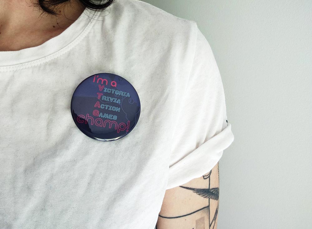 Victoria Trivia Action Games button that says i'm a victoria trivia action games champ on a person with a white shirt.