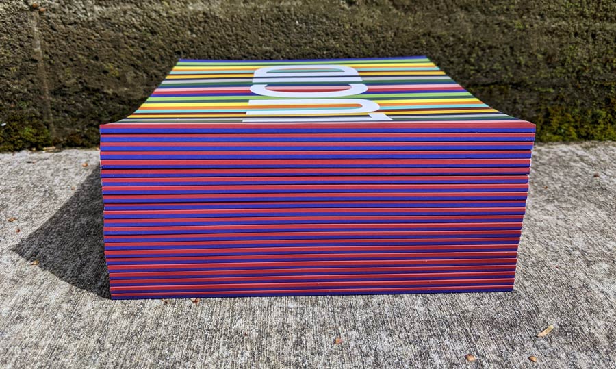 Several Lucid catalogues stacked up emphasizing purple and red spines.